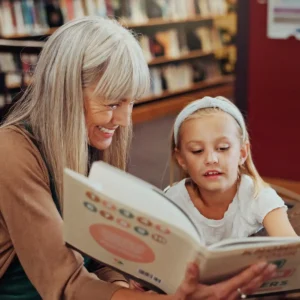 Senior woman reading a book with a young gorl